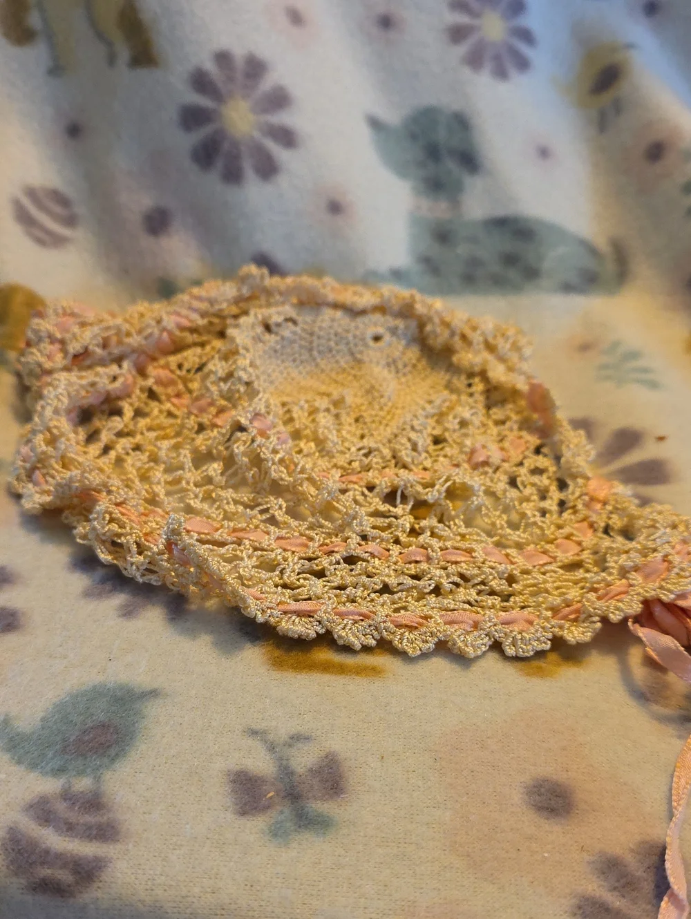 Soft cream crochet bonnet with delicate pink ribbon accents